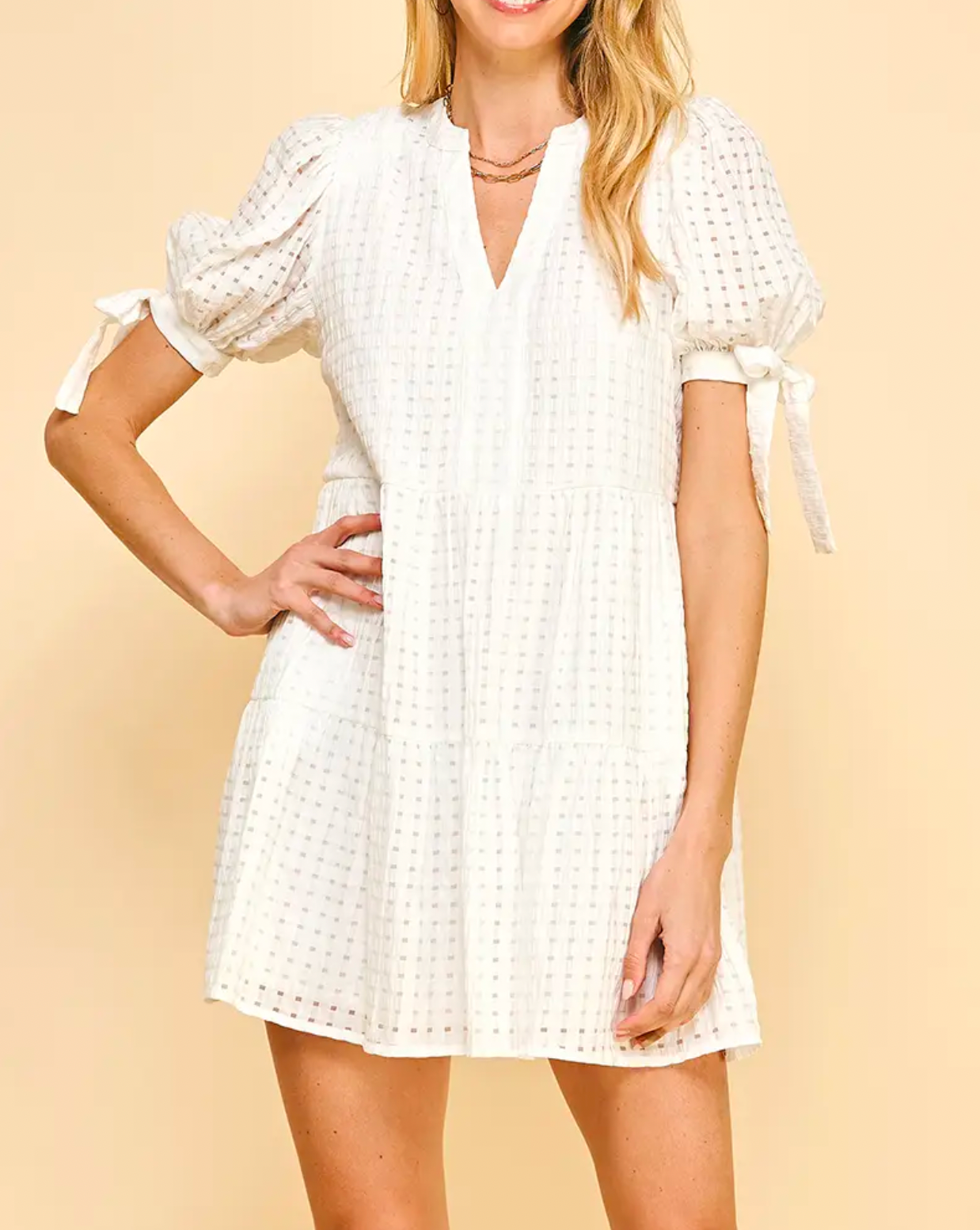 Model wearing Pinch Tunic dress in off white color Puff sleeves with self tie V-neck Tiered Pullover tunic style on a yellow background