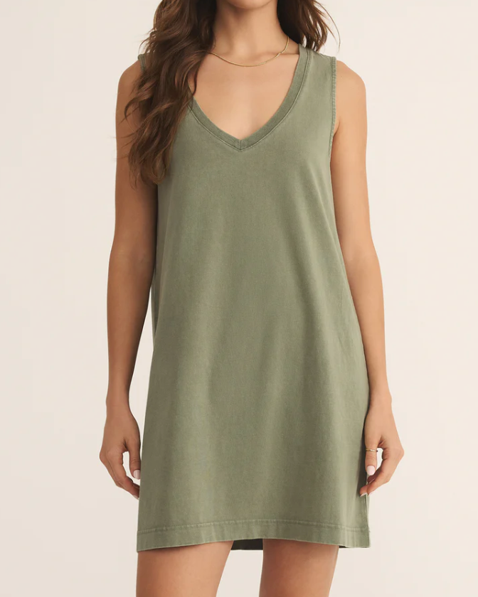 Woman wearing a green sleeveless dress against a plain background