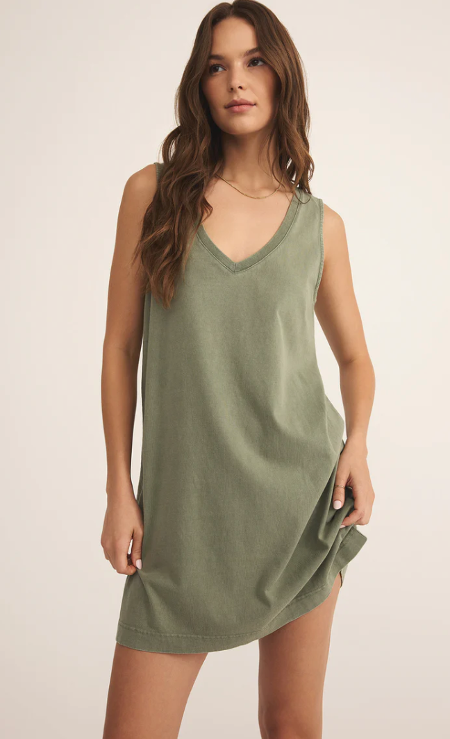 Woman wearing a green sleeveless dress against a plain background