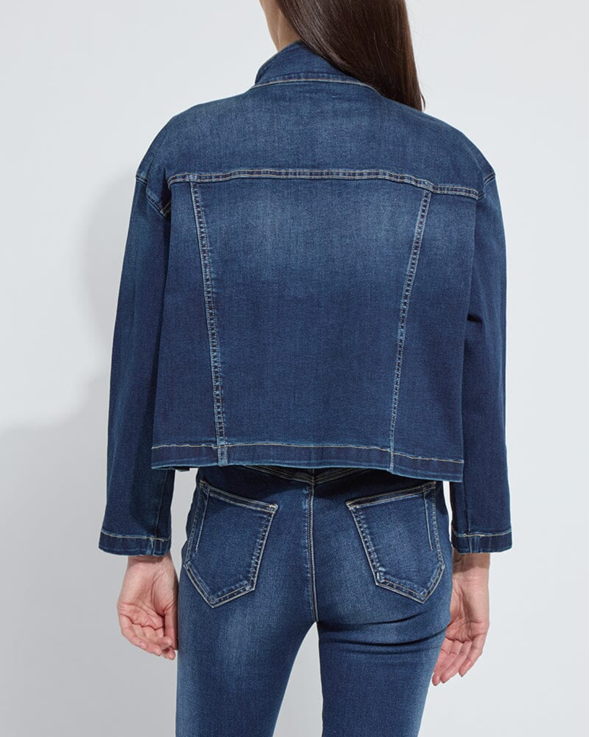 Person wearing a blue denim jacket and jeans on a white background