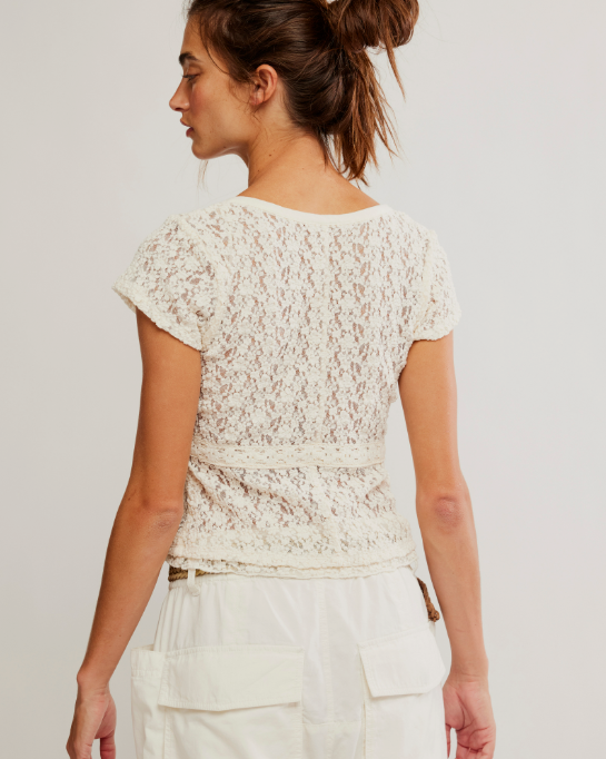 Woman wearing a white lace top and pants against a plain background