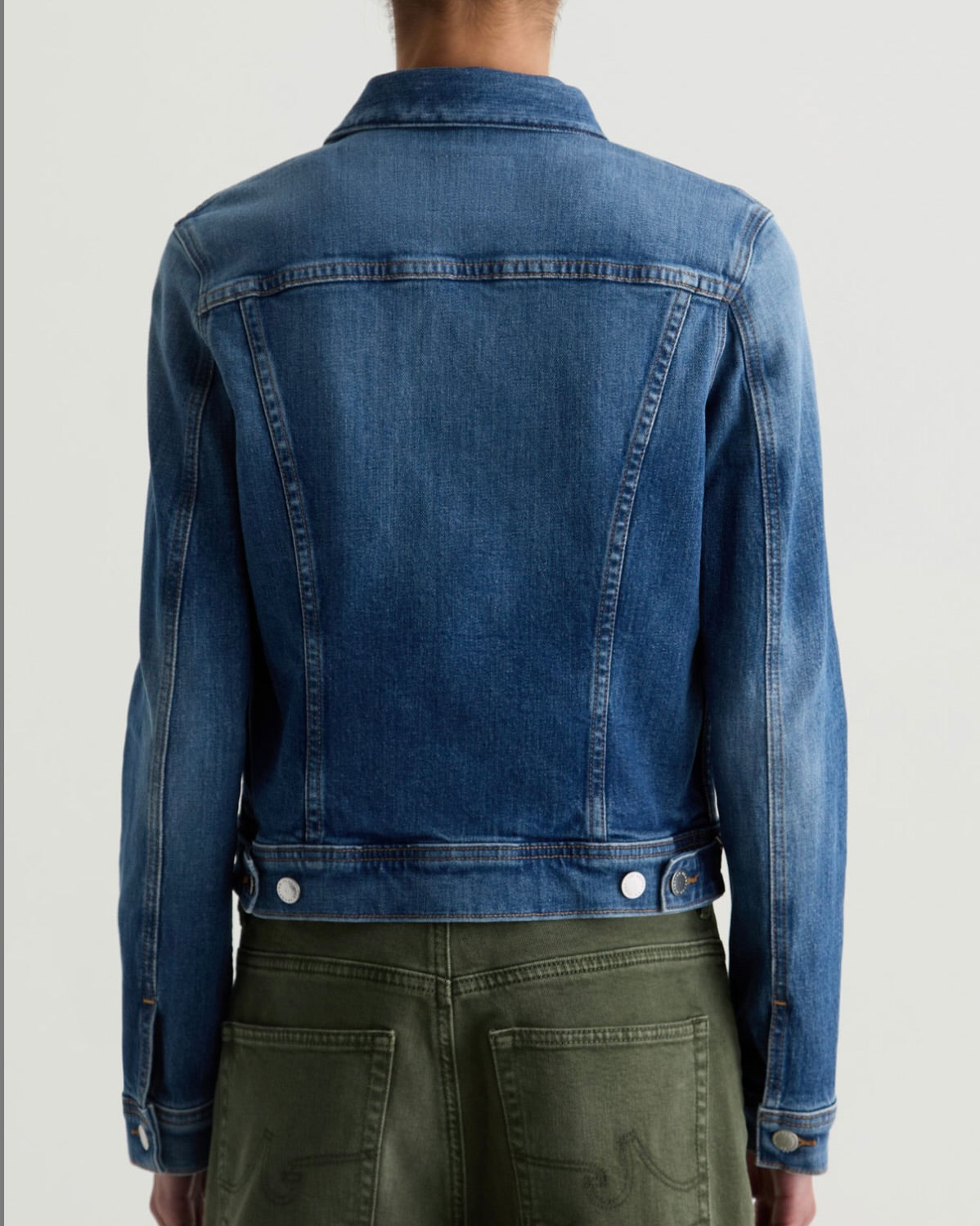 Blue denim jacket worn by a person on a white background
