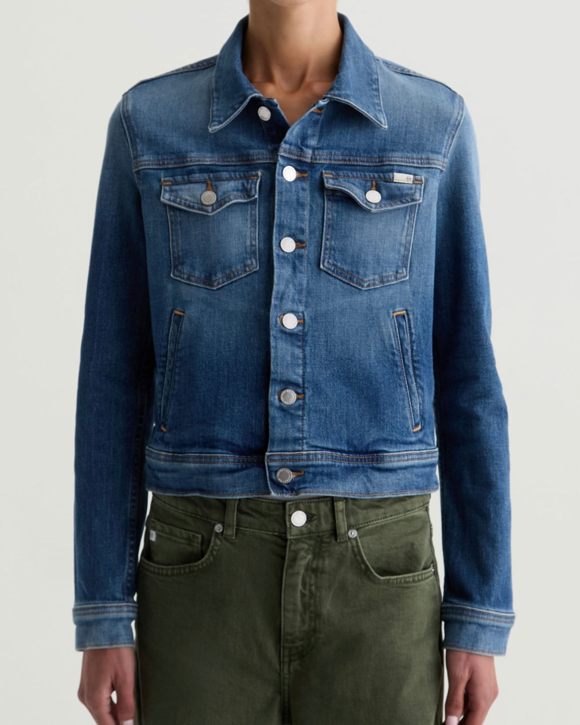 Blue denim jacket worn by a person on a light gray background
