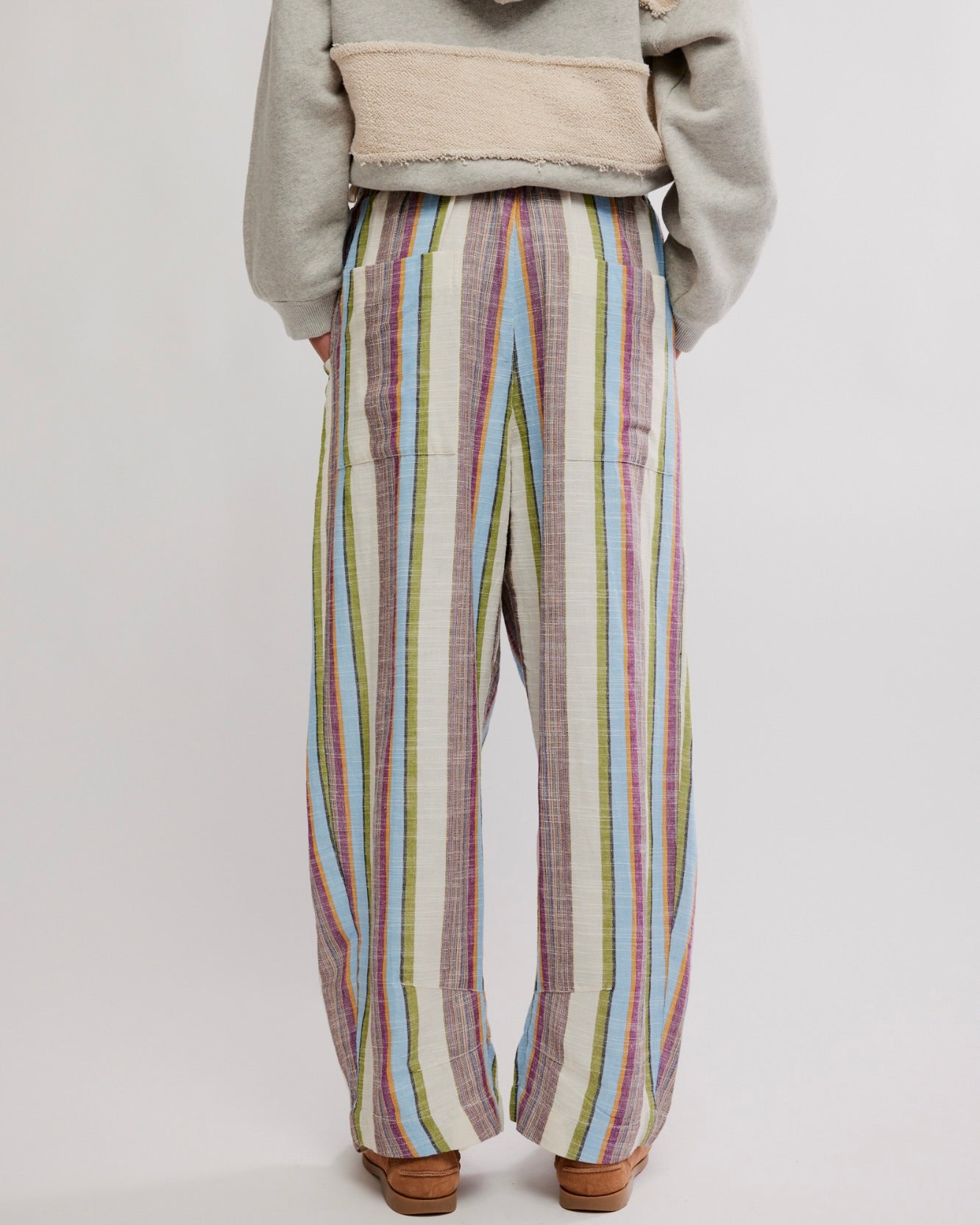 Person wearing colorful striped pants on a plain background