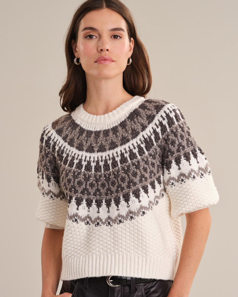 Model wearing the Alora Fair Isle sweater from 525 America standing in front of a white wall.