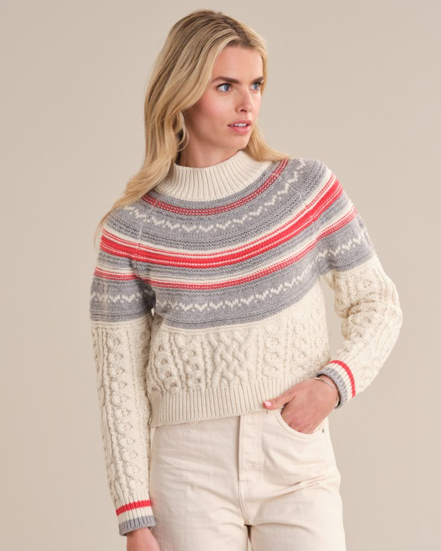 Model wearing the Ayana sweater from 525 America in SEA SALT COMBO with white jeans standing in front of a white background.