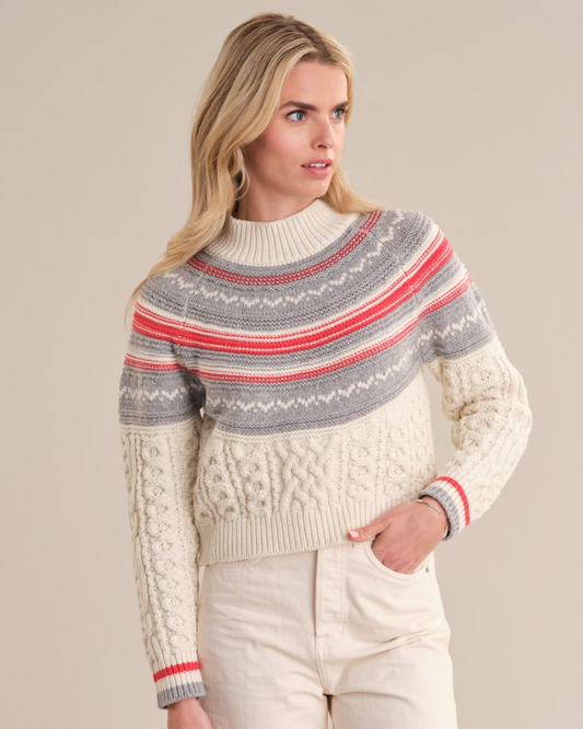 Model wearing the Ayana sweater from 525 America in SEA SALT COMBO with white jeans standing in front of a white background.