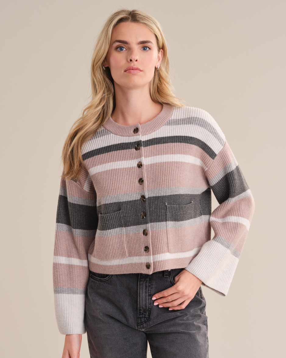 Model wearing the Dana Strip Cardigan from 525 America in NEUTRAL STRIPE with black jeans standing in front of a white background