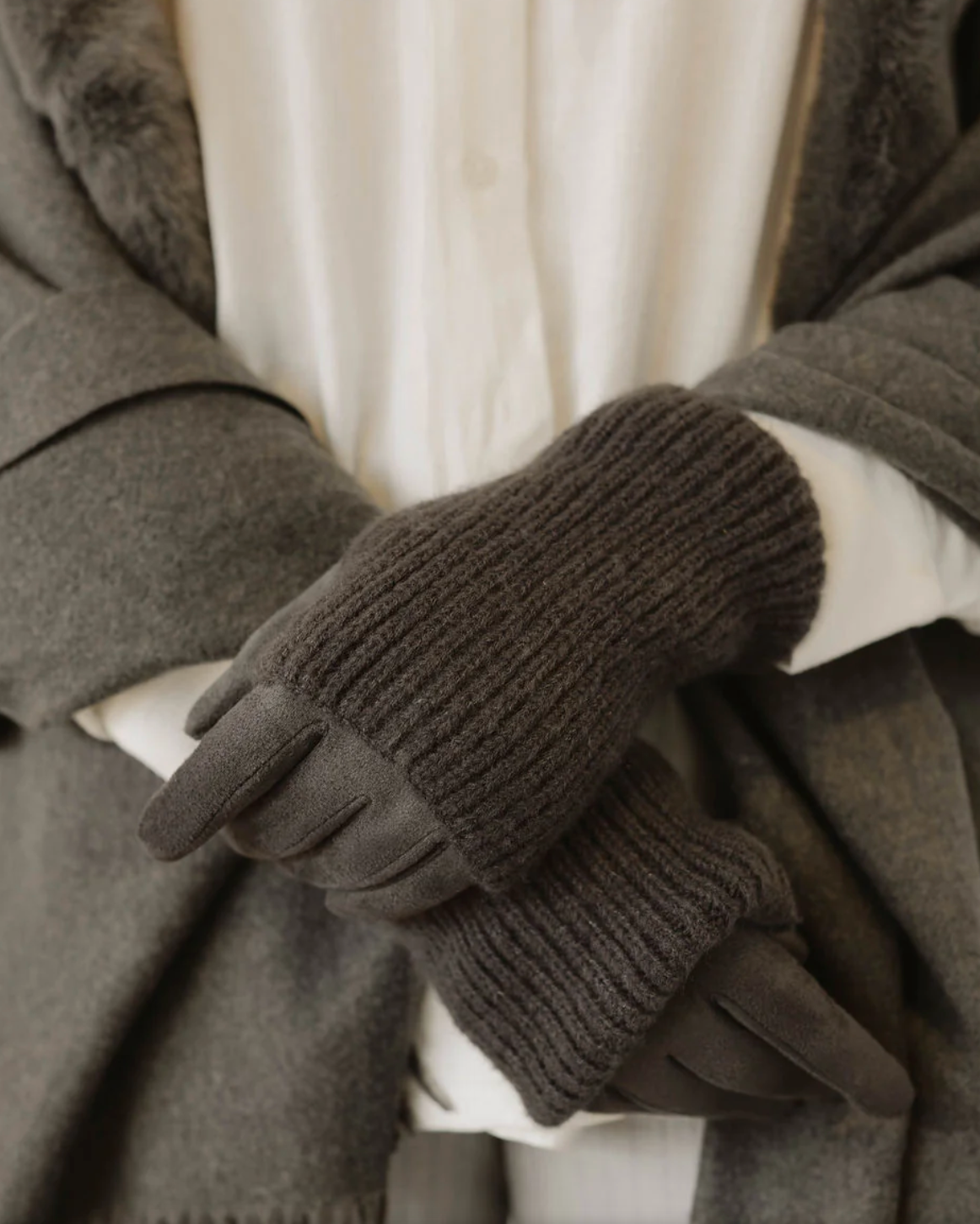 Brown knitted gloves worn with a gray coat and white shirt.