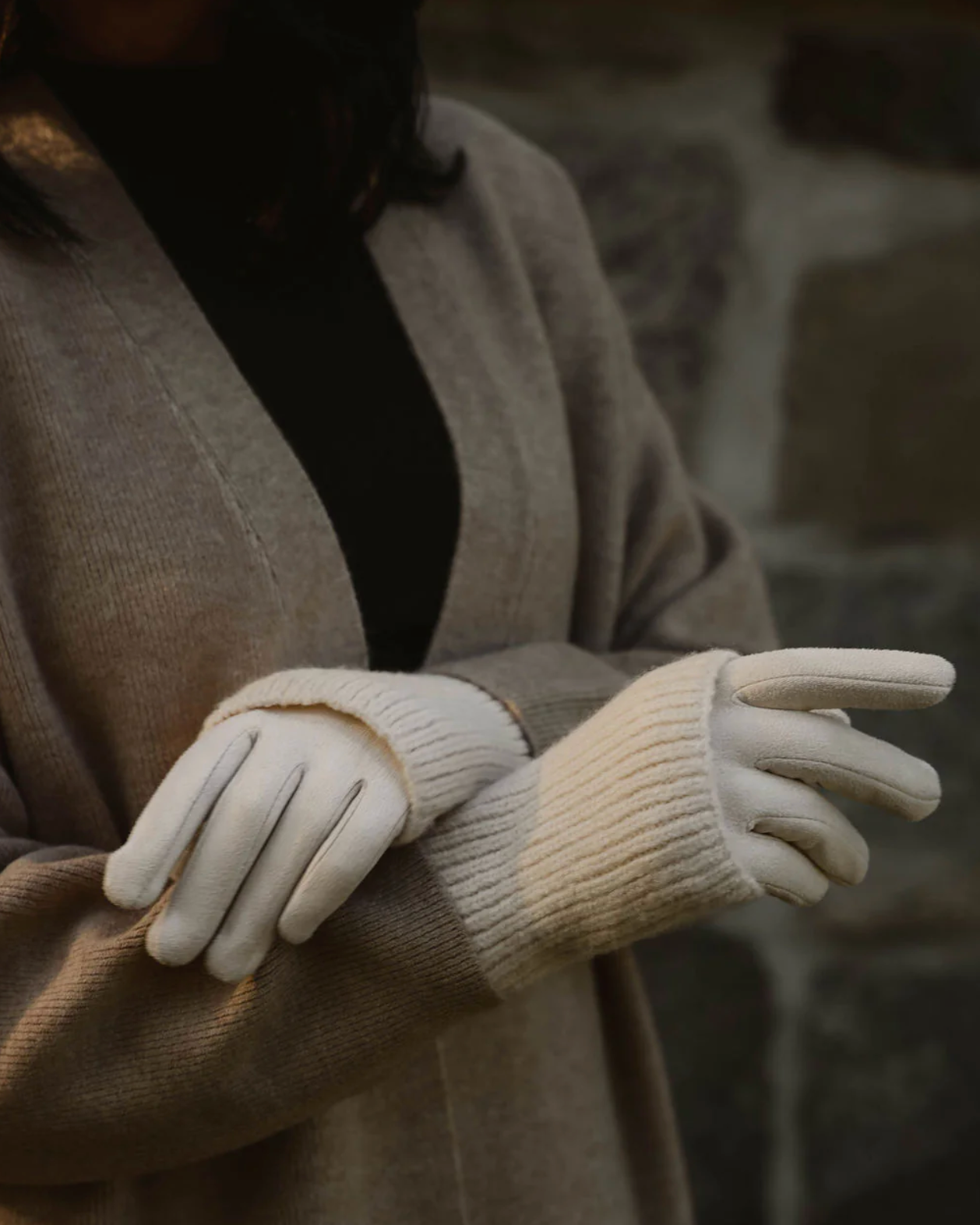 Person wearing beige gloves and a coat with a blurred background