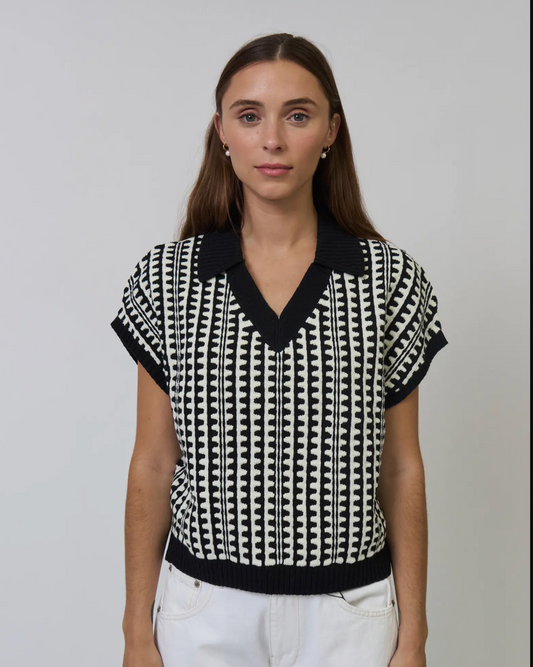 Woman wearing a black and white patterned top against a plain background