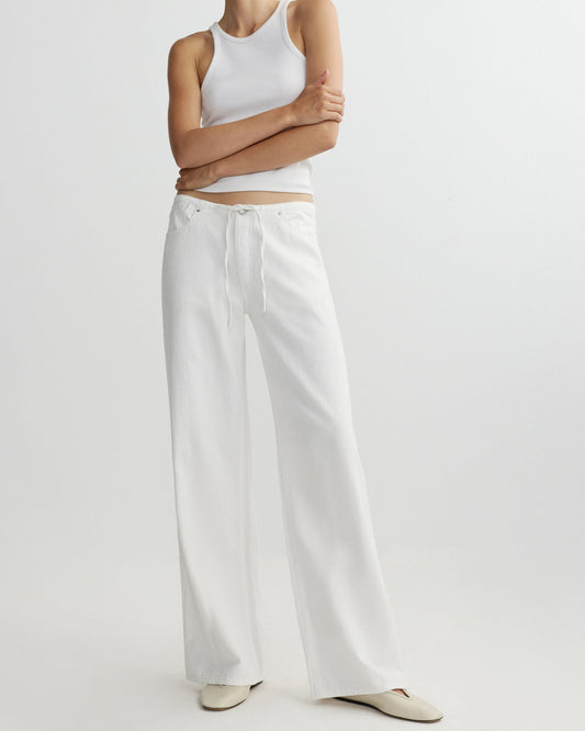 Person wearing a white tank top and wide-leg pants on a light gray background