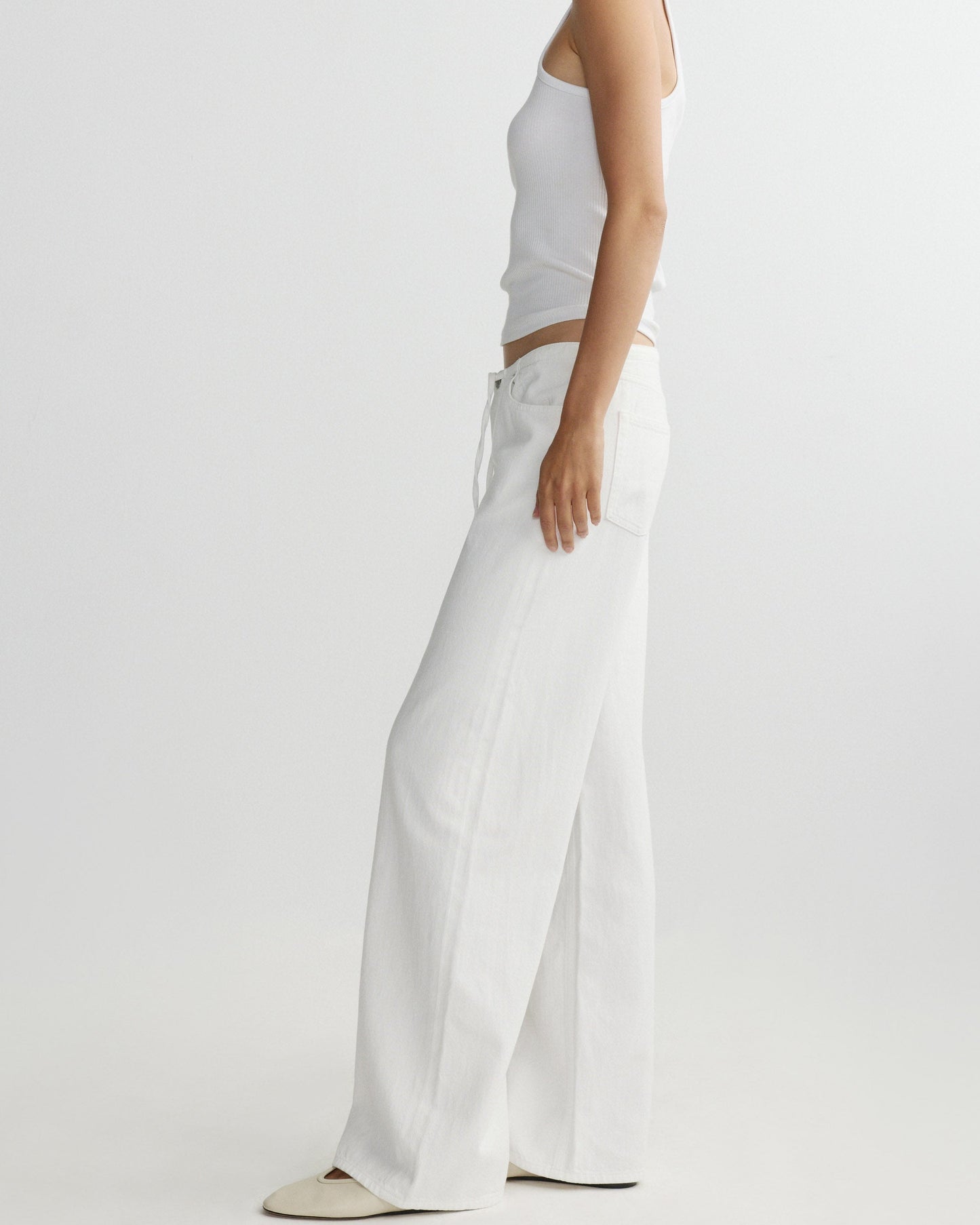 Person wearing a white top and wide-leg pants on a plain background