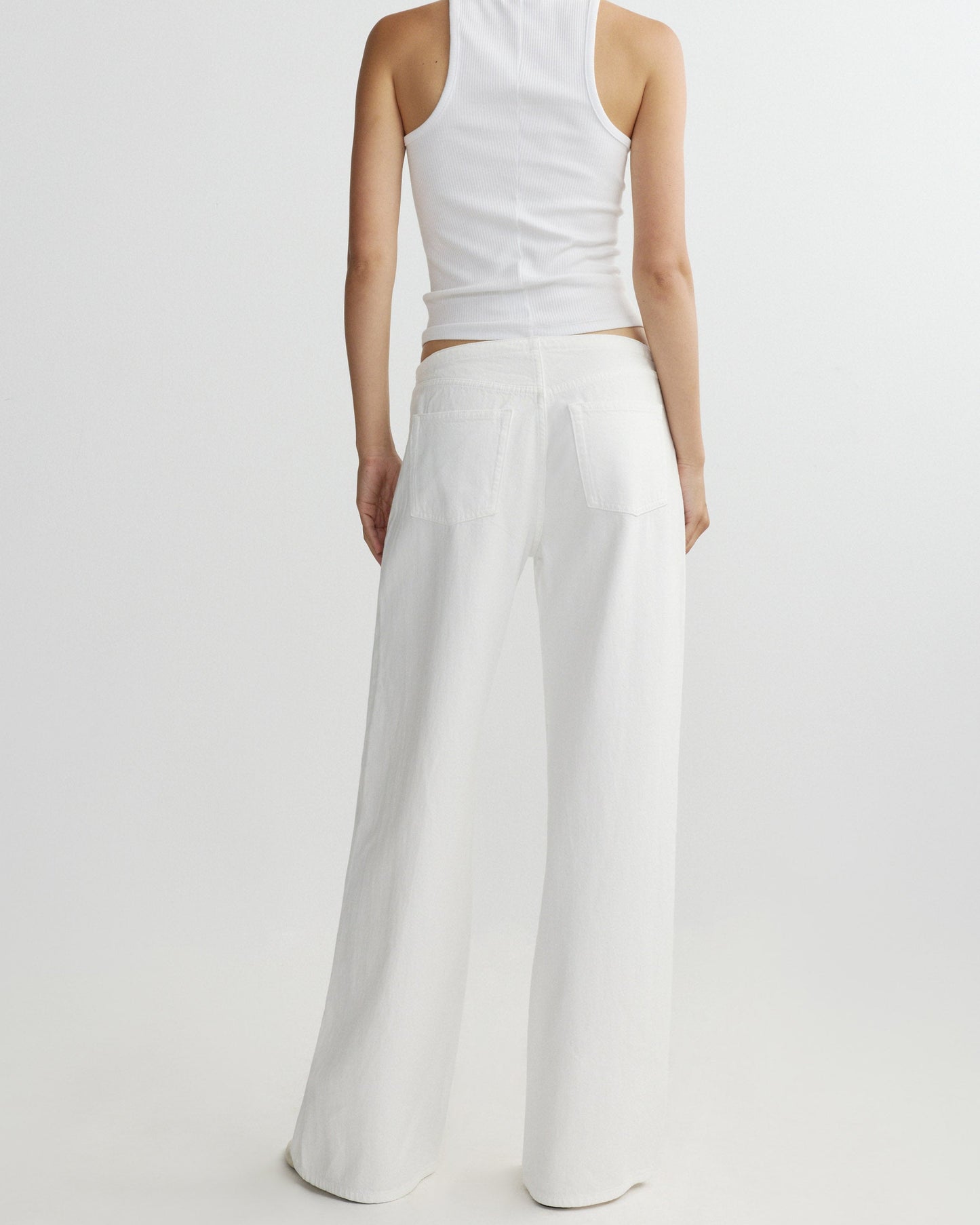 Person wearing a white sleeveless top and wide-leg pants on a light gray background