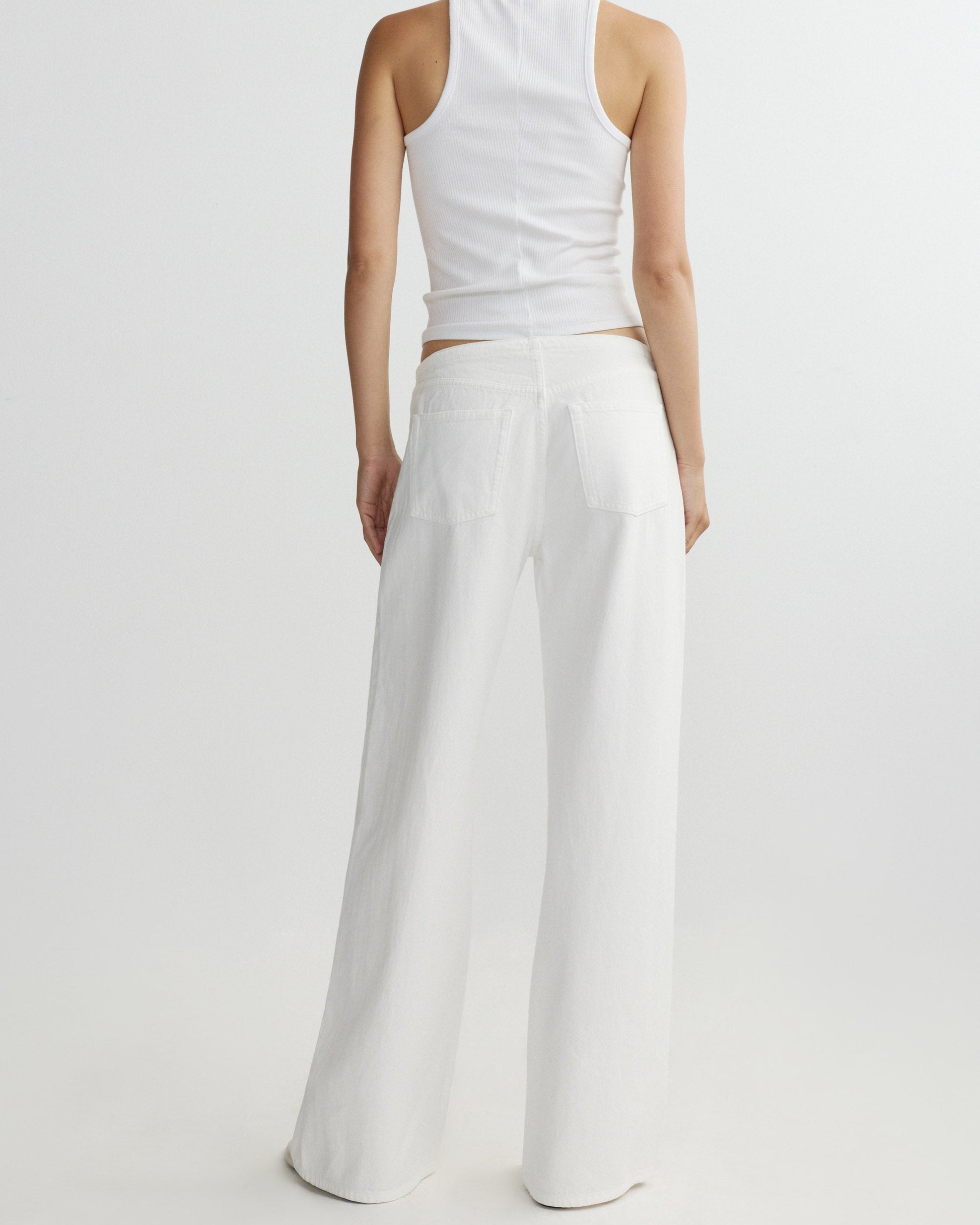 Person wearing a white sleeveless top and wide-leg pants on a light gray background