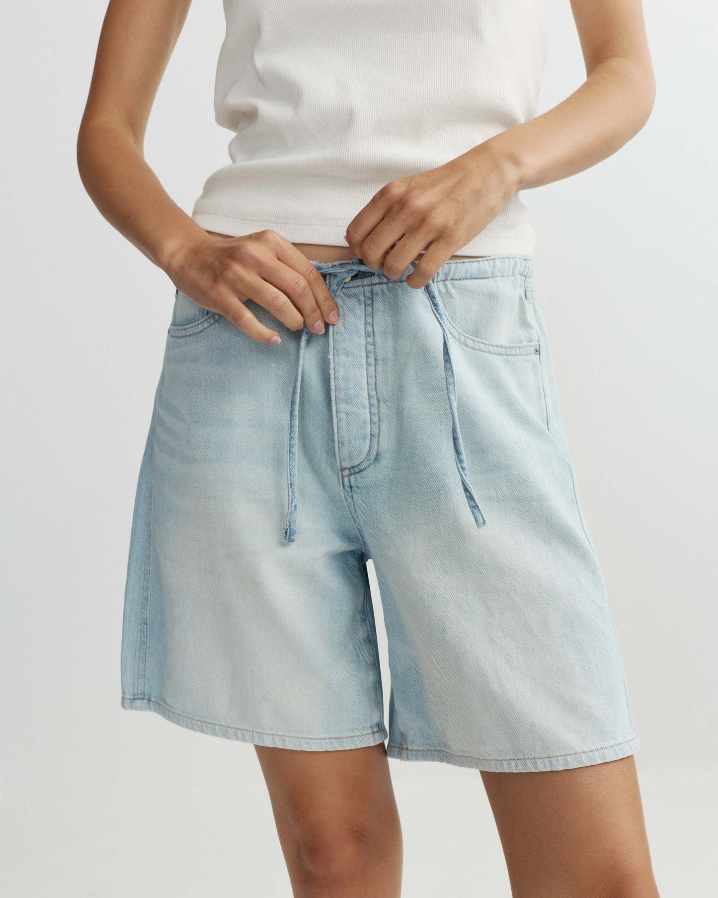 Light blue denim shorts worn by a person on a plain background