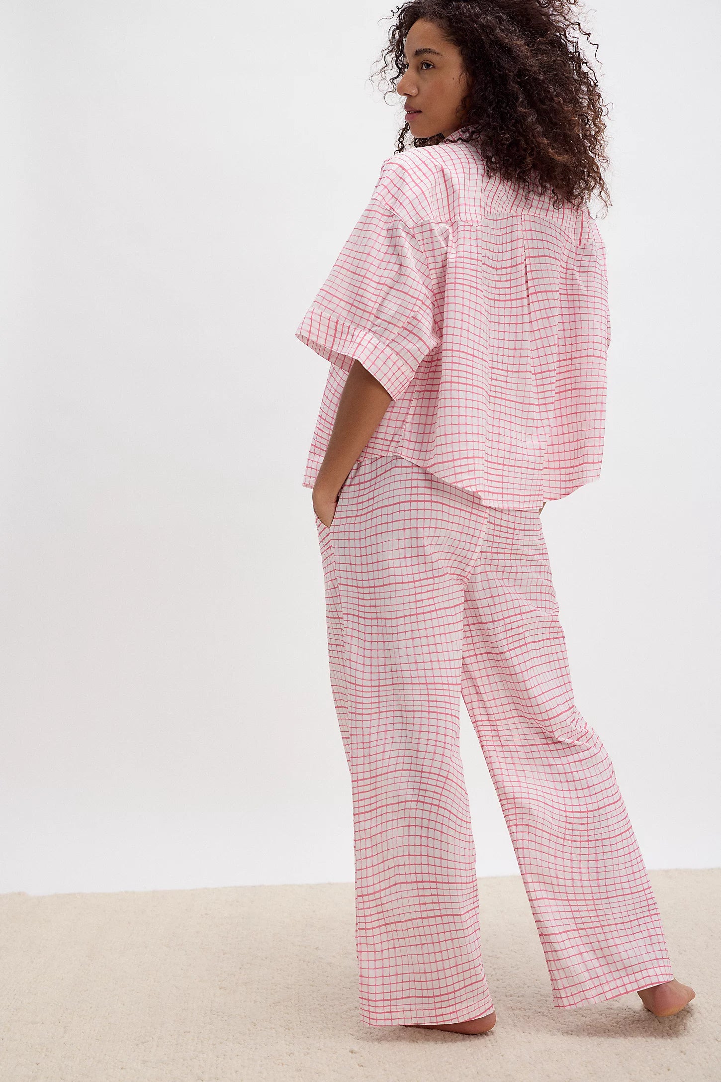 Person wearing a pink checkered outfit on a white background