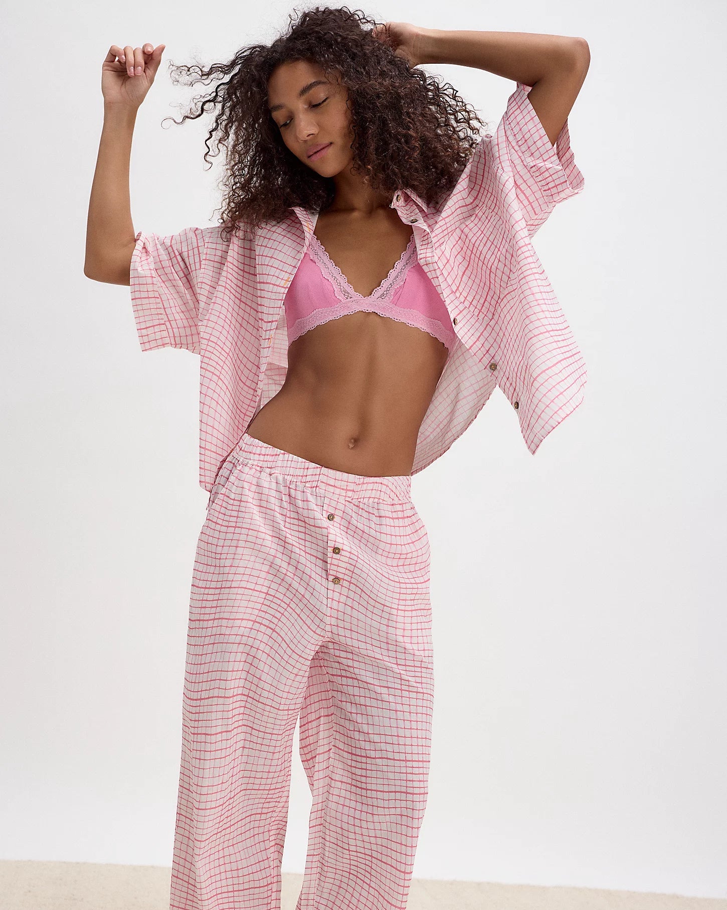 Woman wearing a pink checkered kimono and pants on a white background