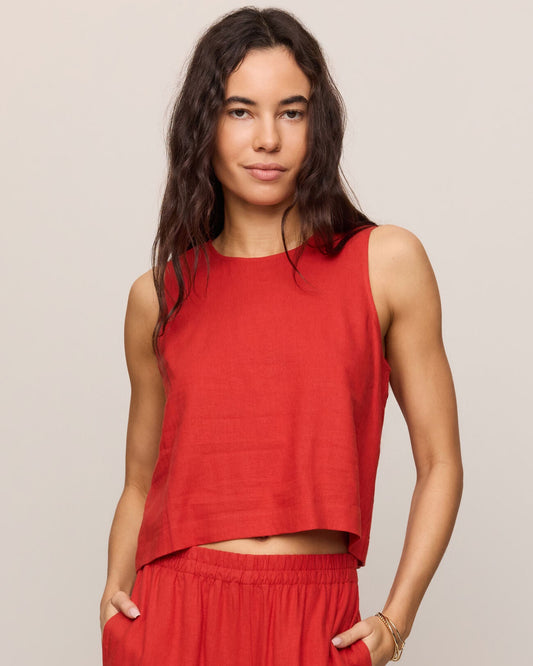 Woman wearing a red sleeveless top and wide-leg pants against a beige background