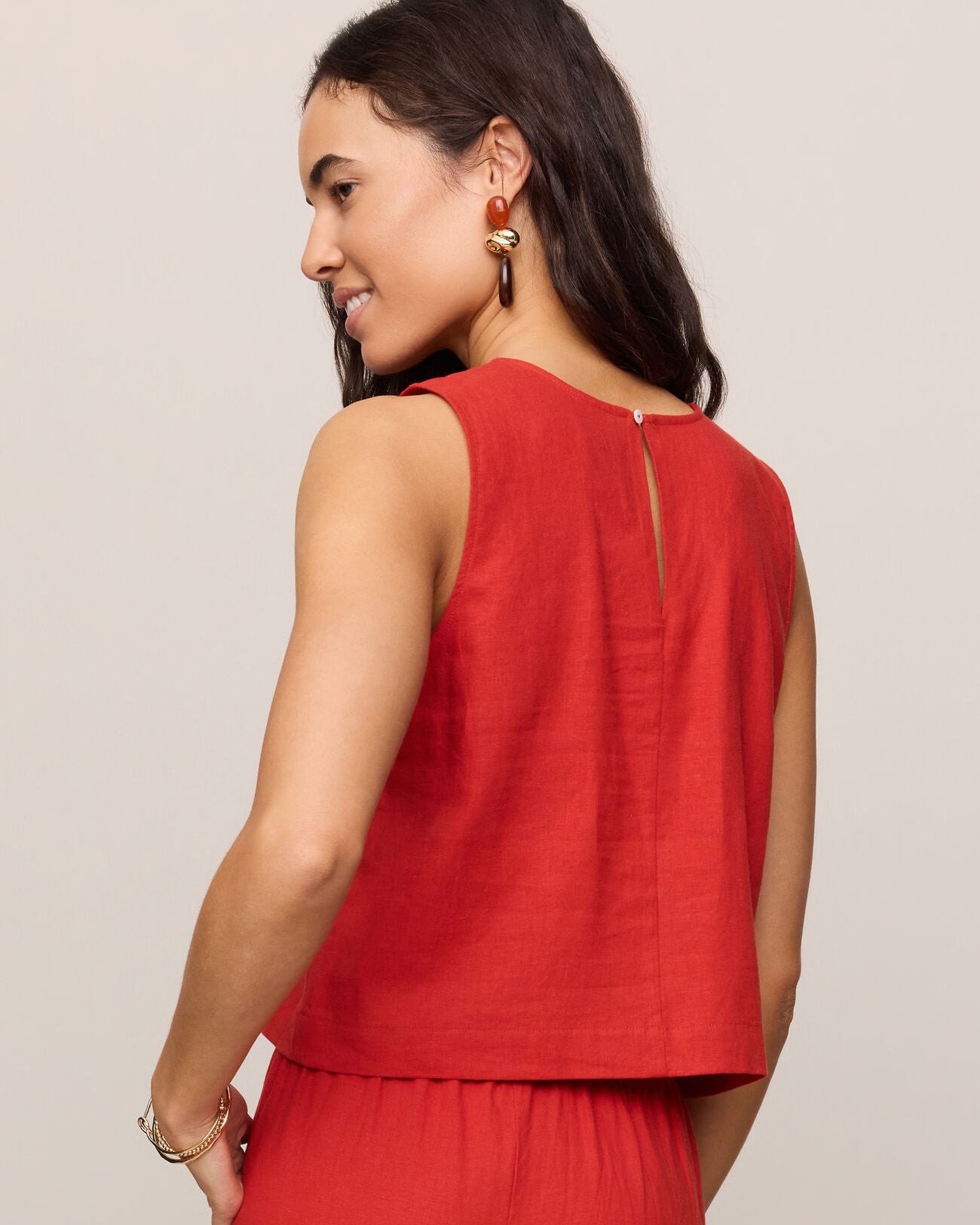 Woman wearing a red sleeveless top and pants against a plain background