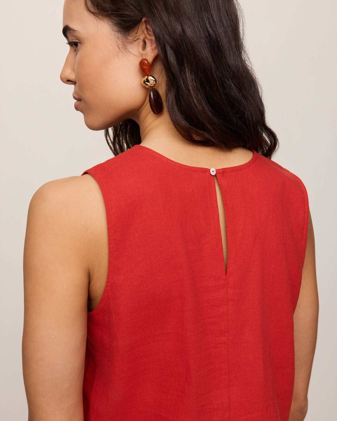 Woman wearing a red sleeveless top with a plain background