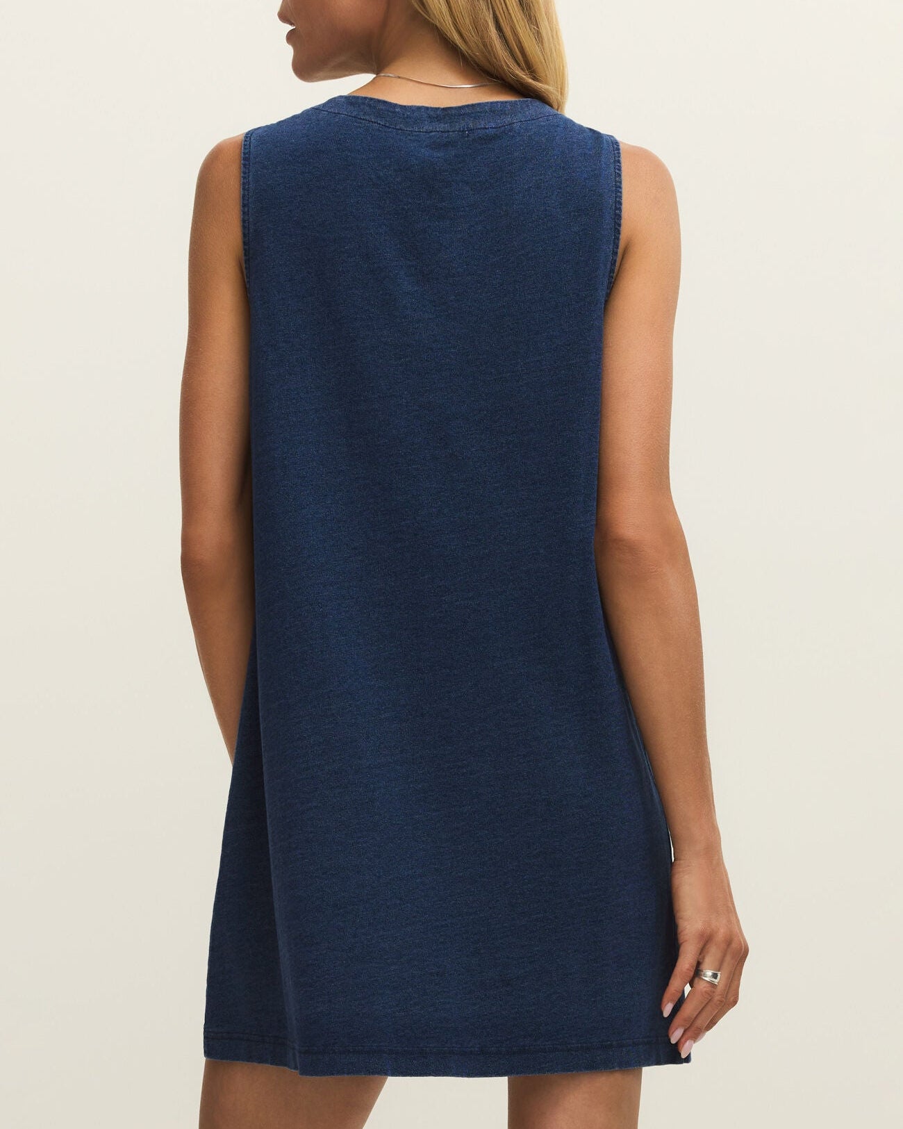 Woman wearing a blue sleeveless dress against a plain background