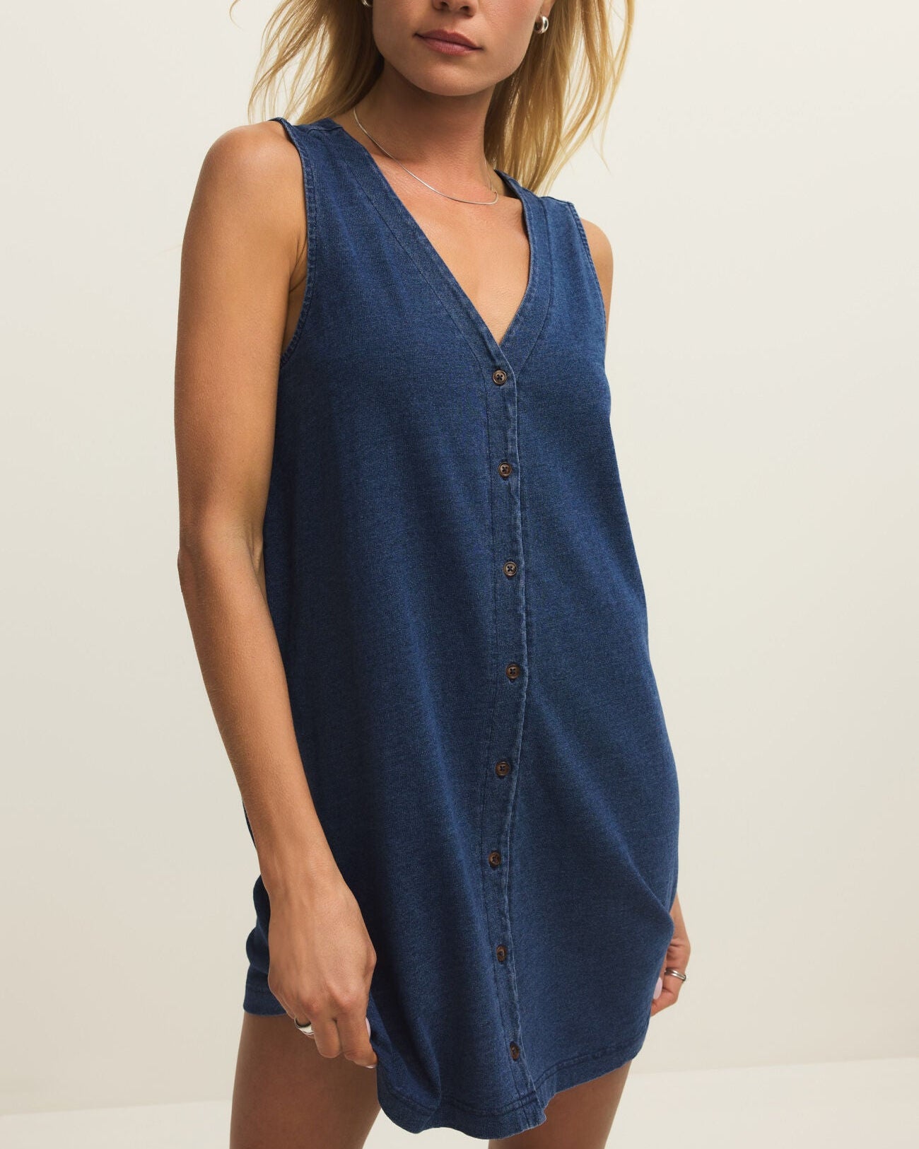 Woman wearing a blue sleeveless dress against a plain background