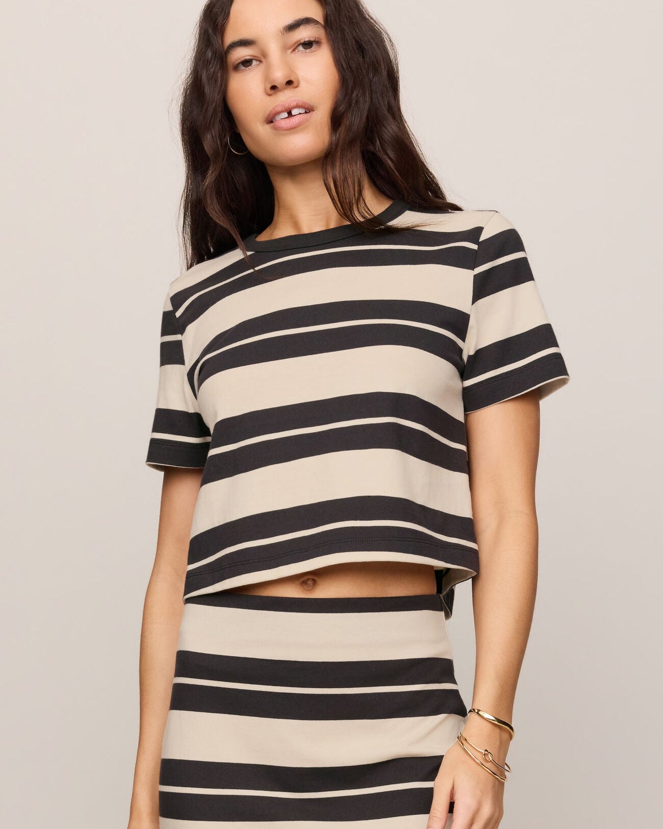 Woman wearing a black and beige striped outfit on a plain background