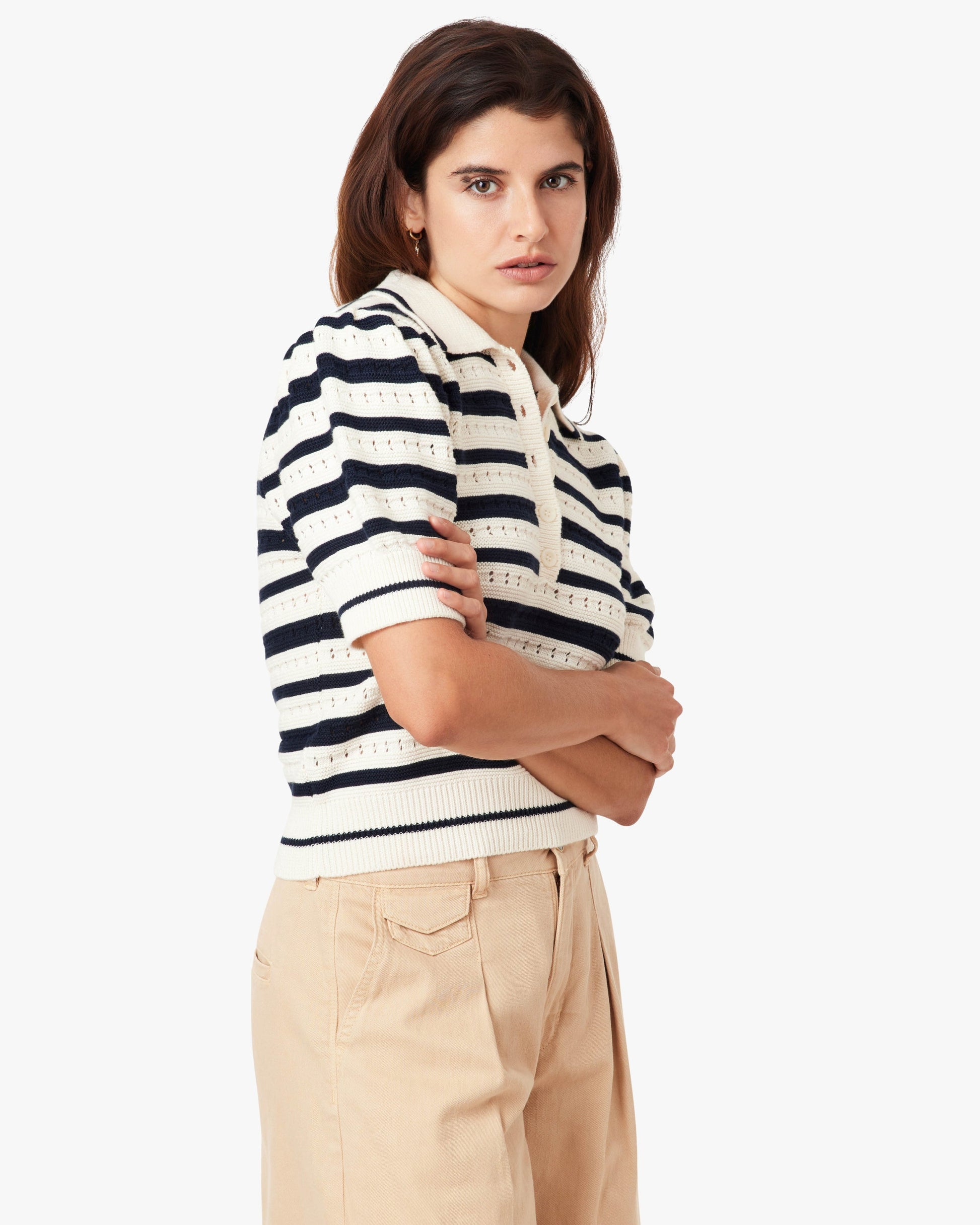 Woman wearing a black and white striped shirt with beige pants on a white background