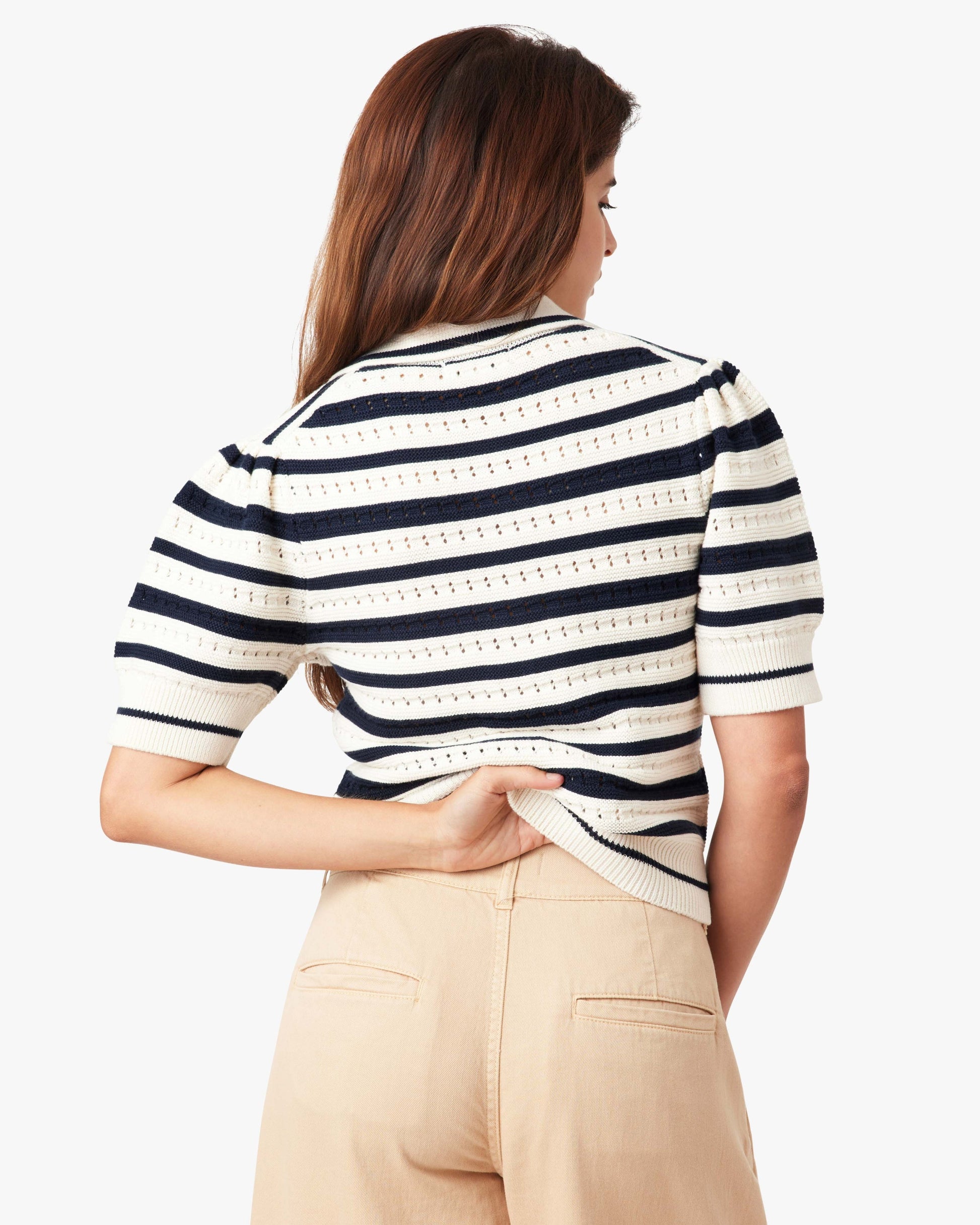 Woman wearing a striped shirt and beige pants on a white background
