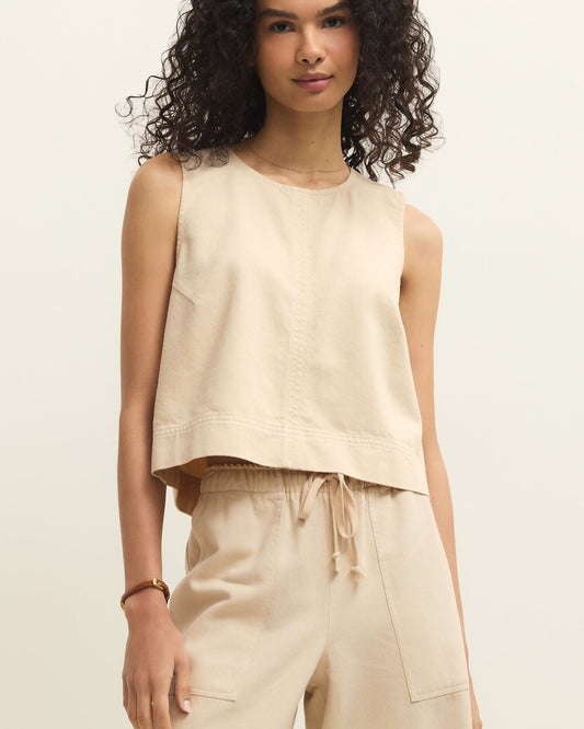 Woman wearing a beige sleeveless top and pants against a neutral background