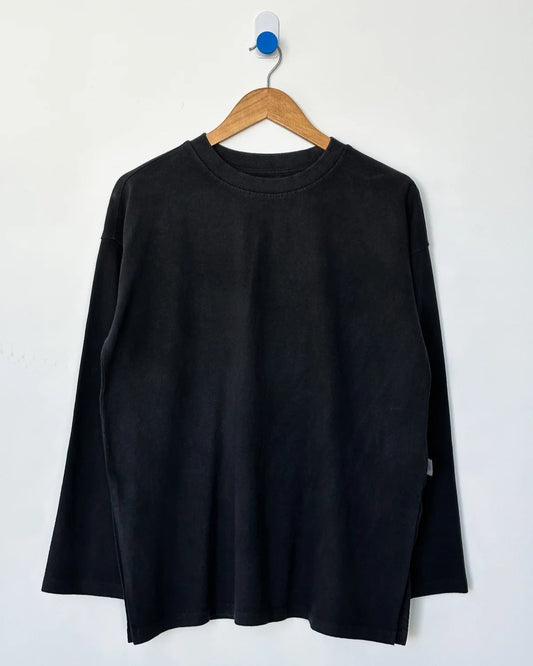 Black long-sleeve shirt on a wooden hanger against a white background