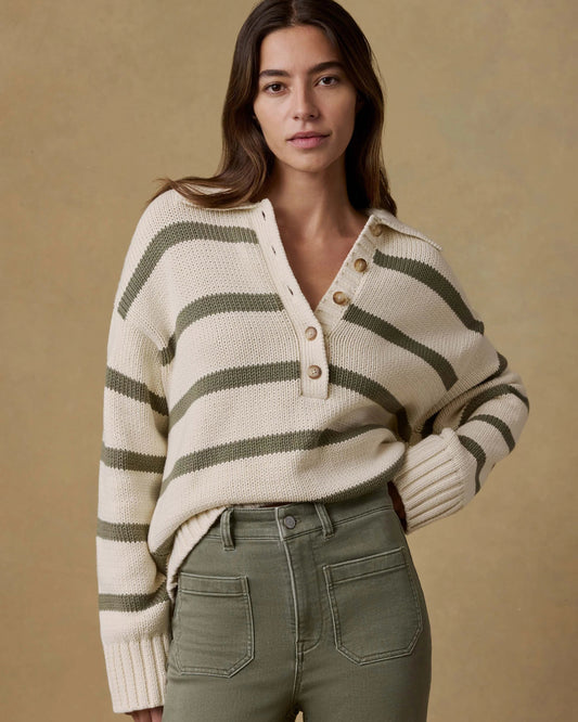 Woman wearing a striped sweater and green pants against a beige background