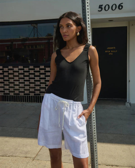 Woman wearing a black top and white shorts standing outdoors.
