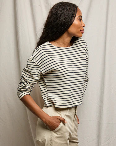 Woman wearing a striped shirt and beige pants against a plain background