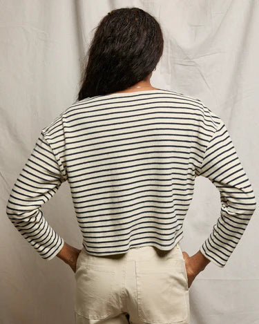 Person wearing a striped shirt and beige pants against a plain background