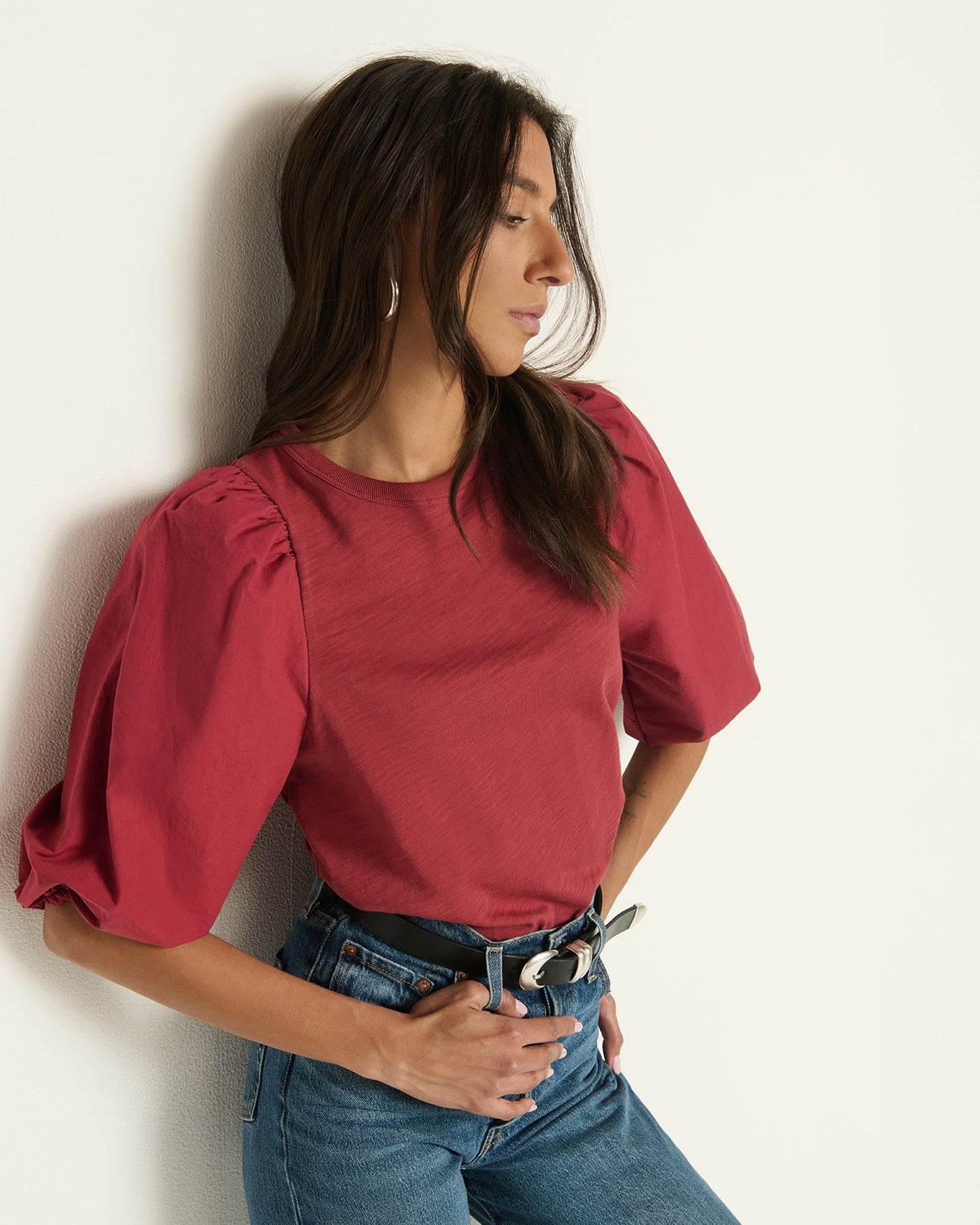 Model wearing Nation Tippi Top in Russet  with blue jeans standing in front of a white background