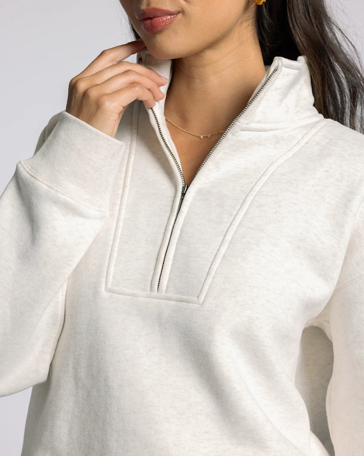 Close-up of a person wearing a white zip-up sweatshirt against a light background