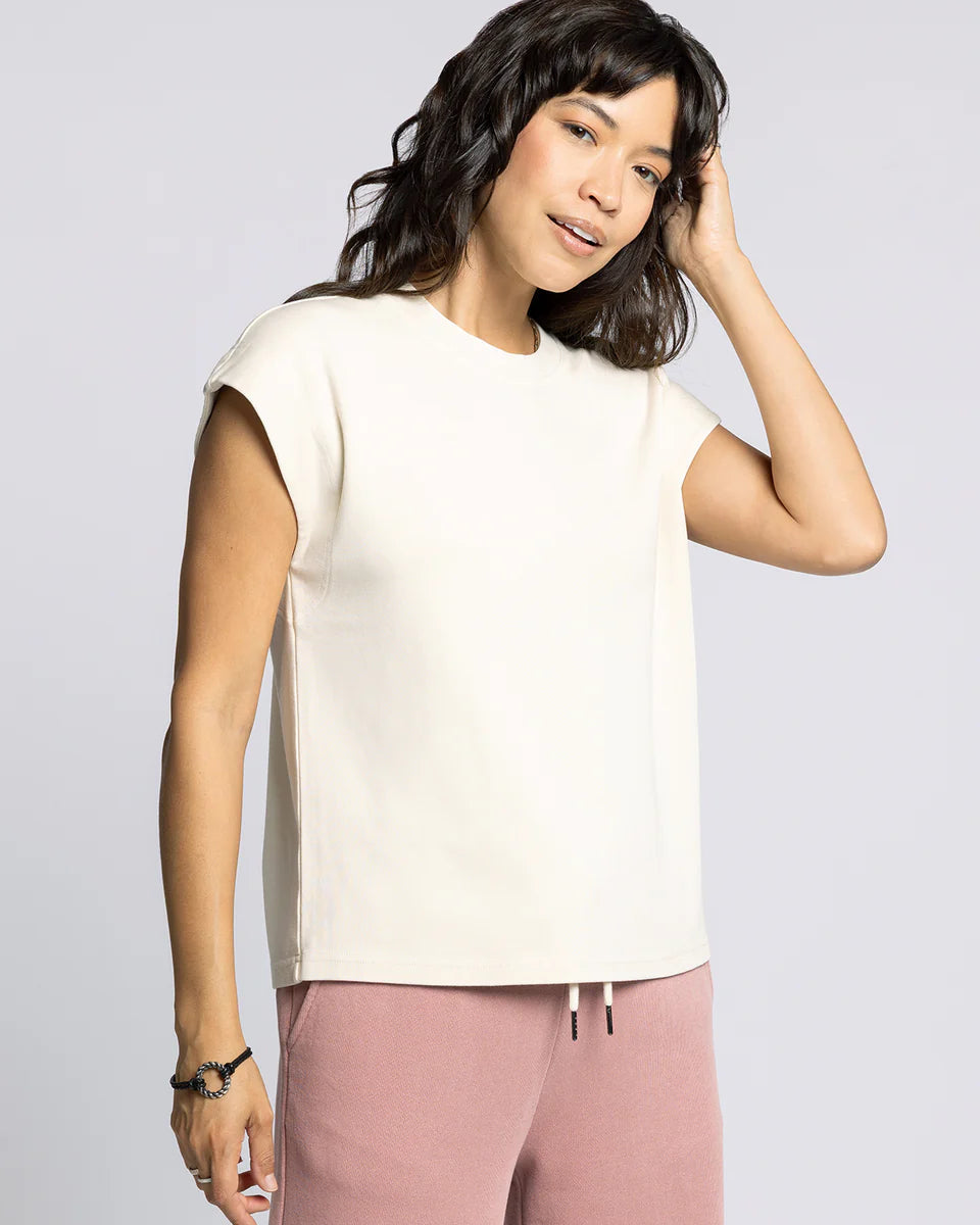 Woman wearing a white top and pink pants against a plain background
