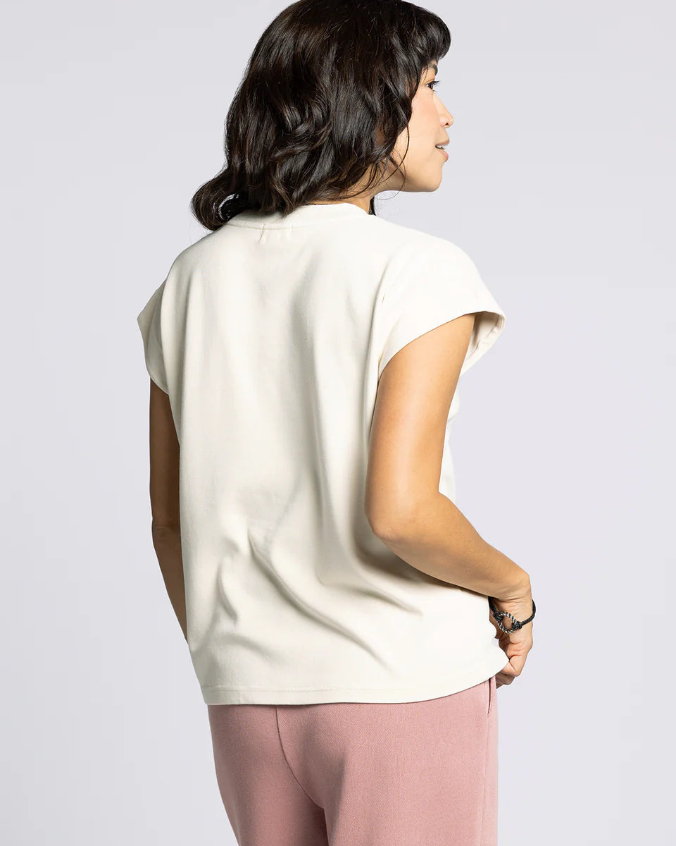 Woman wearing a white top and pink pants on a plain background