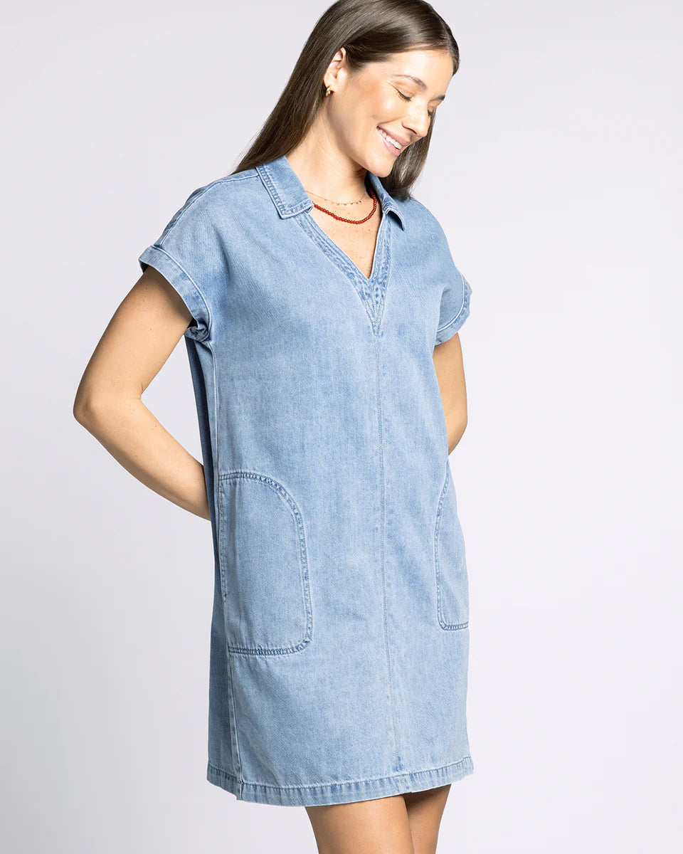 Woman wearing a light blue denim dress on a plain background