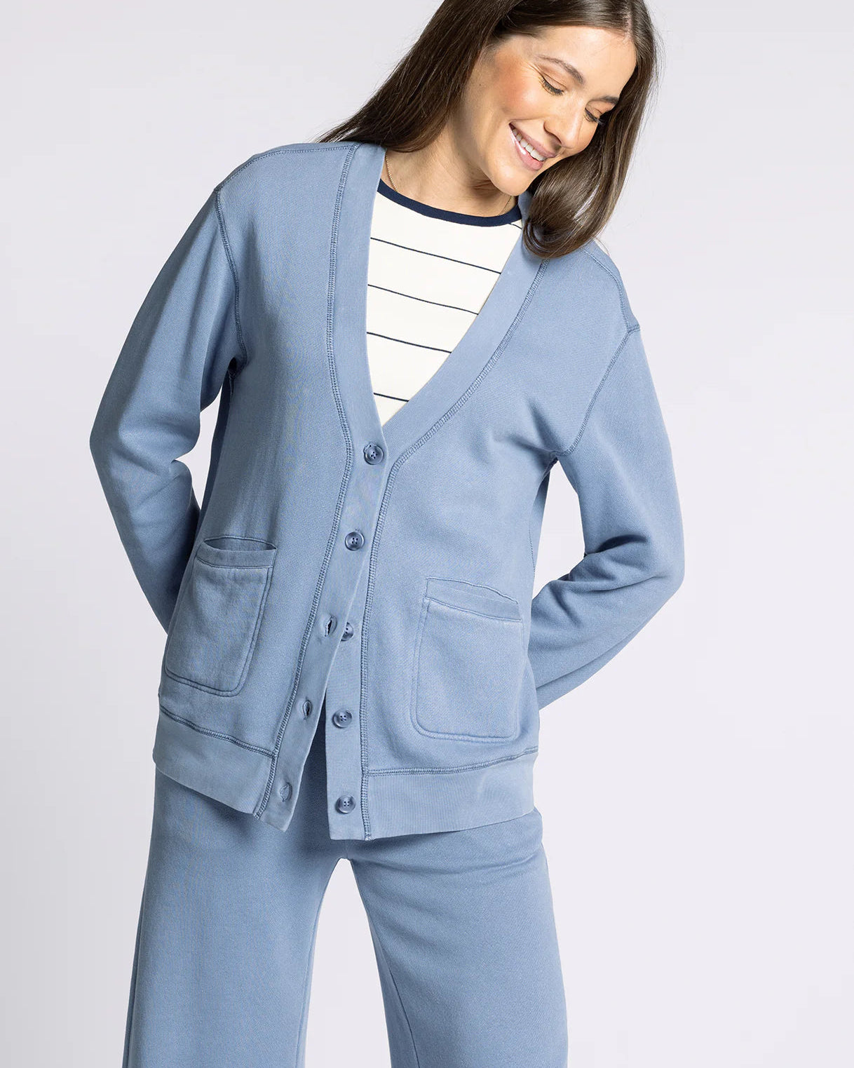 Woman wearing a light blue cardigan and pants on a plain background
