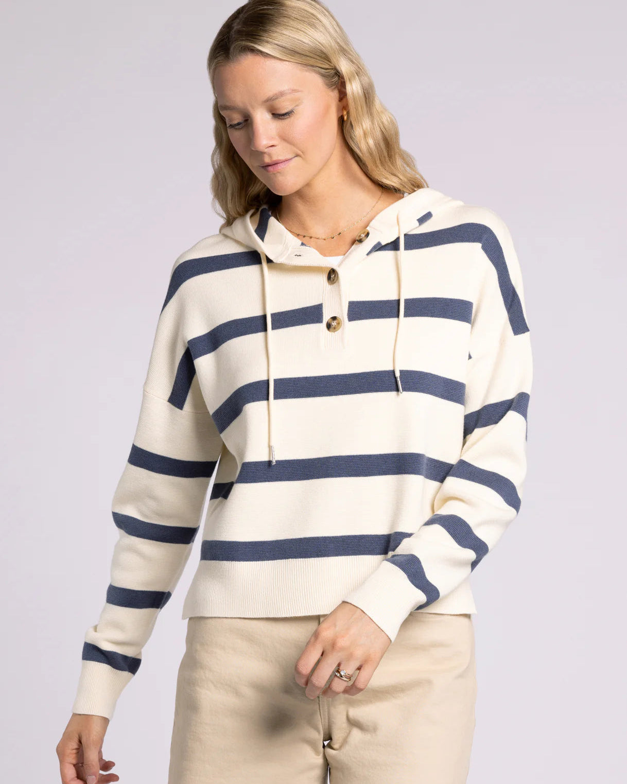Woman wearing a cream and navy striped hoodie on a light gray background