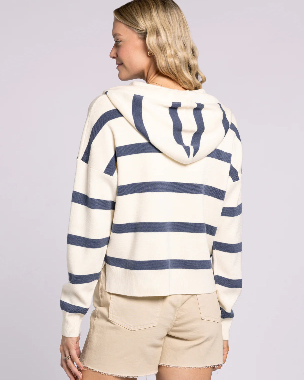 Person wearing a striped hoodie and shorts on a plain background