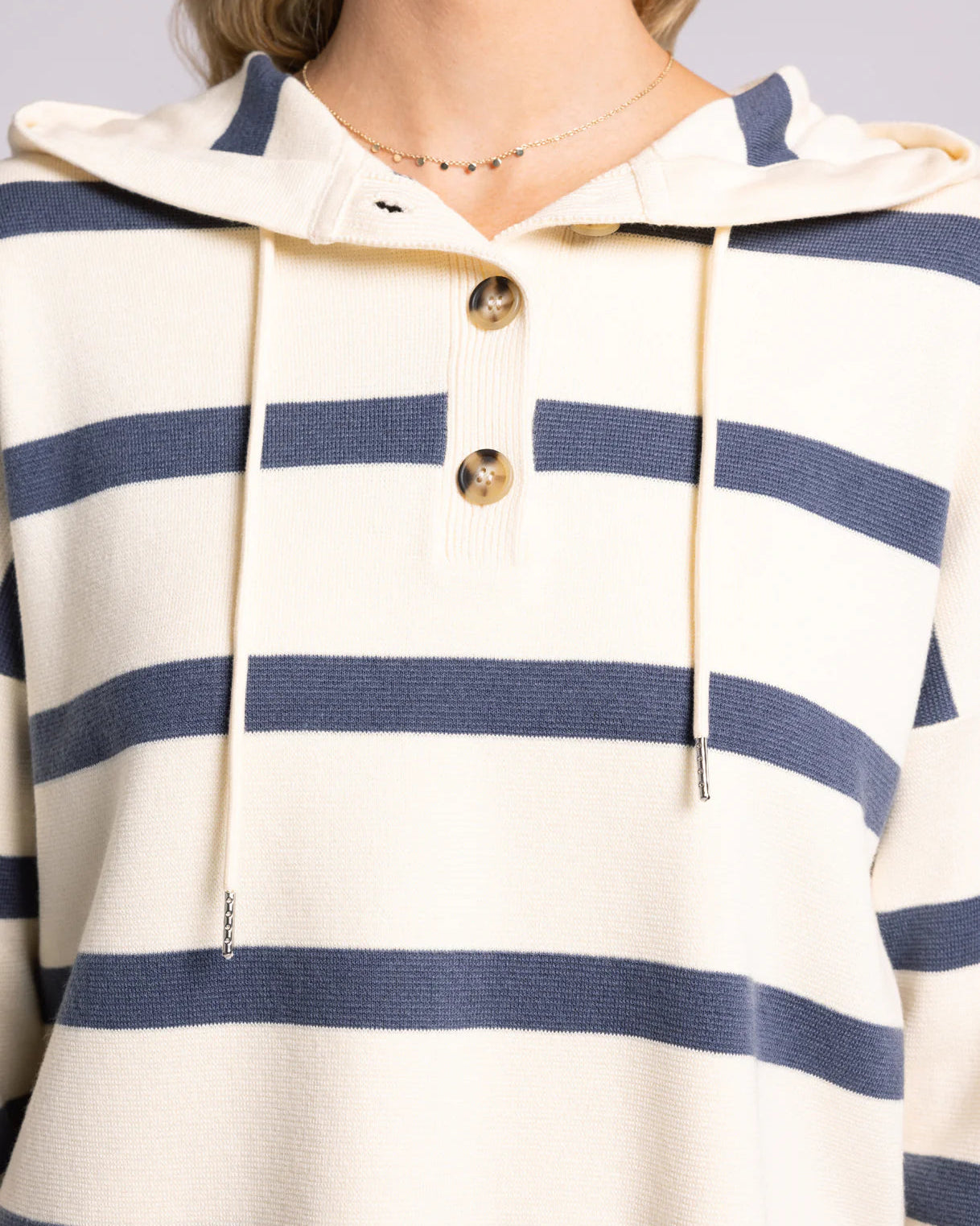 Close-up of a person wearing a striped hoodie with blue and white horizontal stripes.