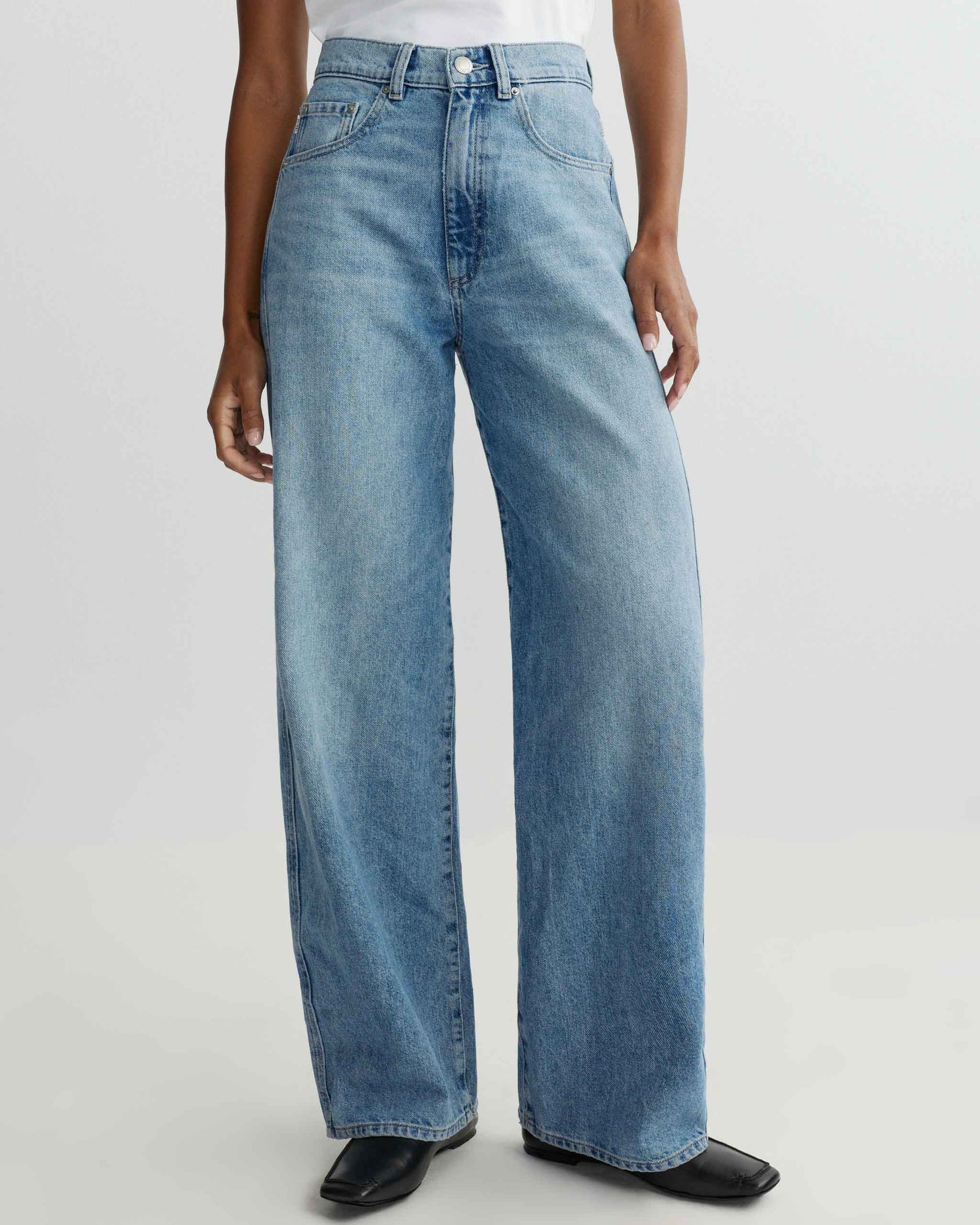 Person wearing light blue jeans on a white background