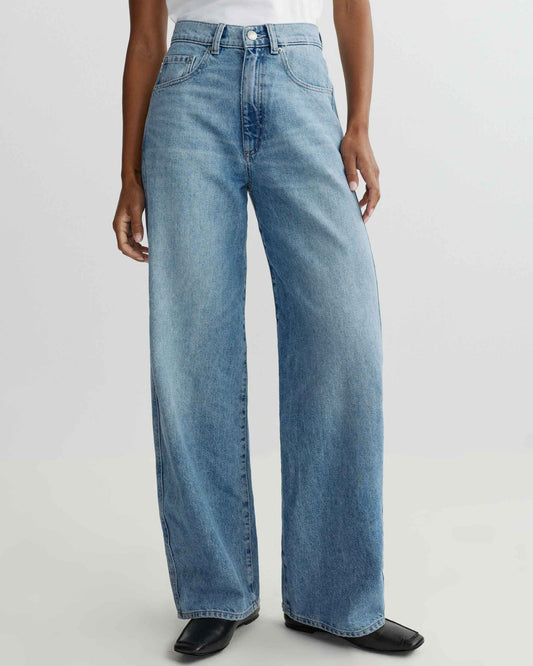 Person wearing light blue jeans on a white background