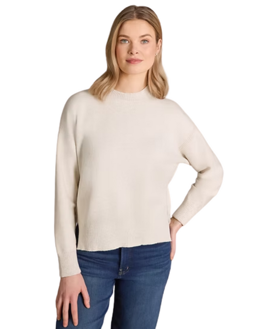 Woman wearing a beige sweater and blue jeans on a white background