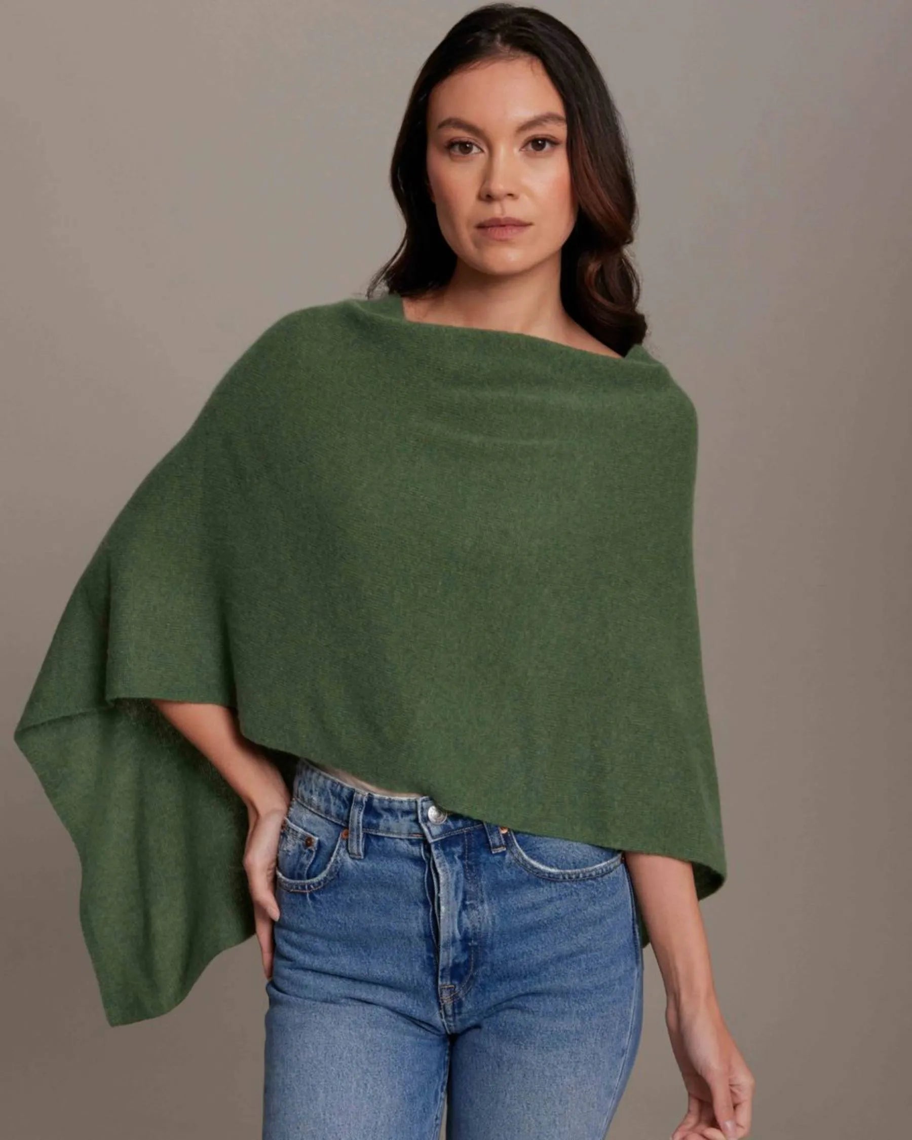 Woman wearing a green poncho over a plain background
