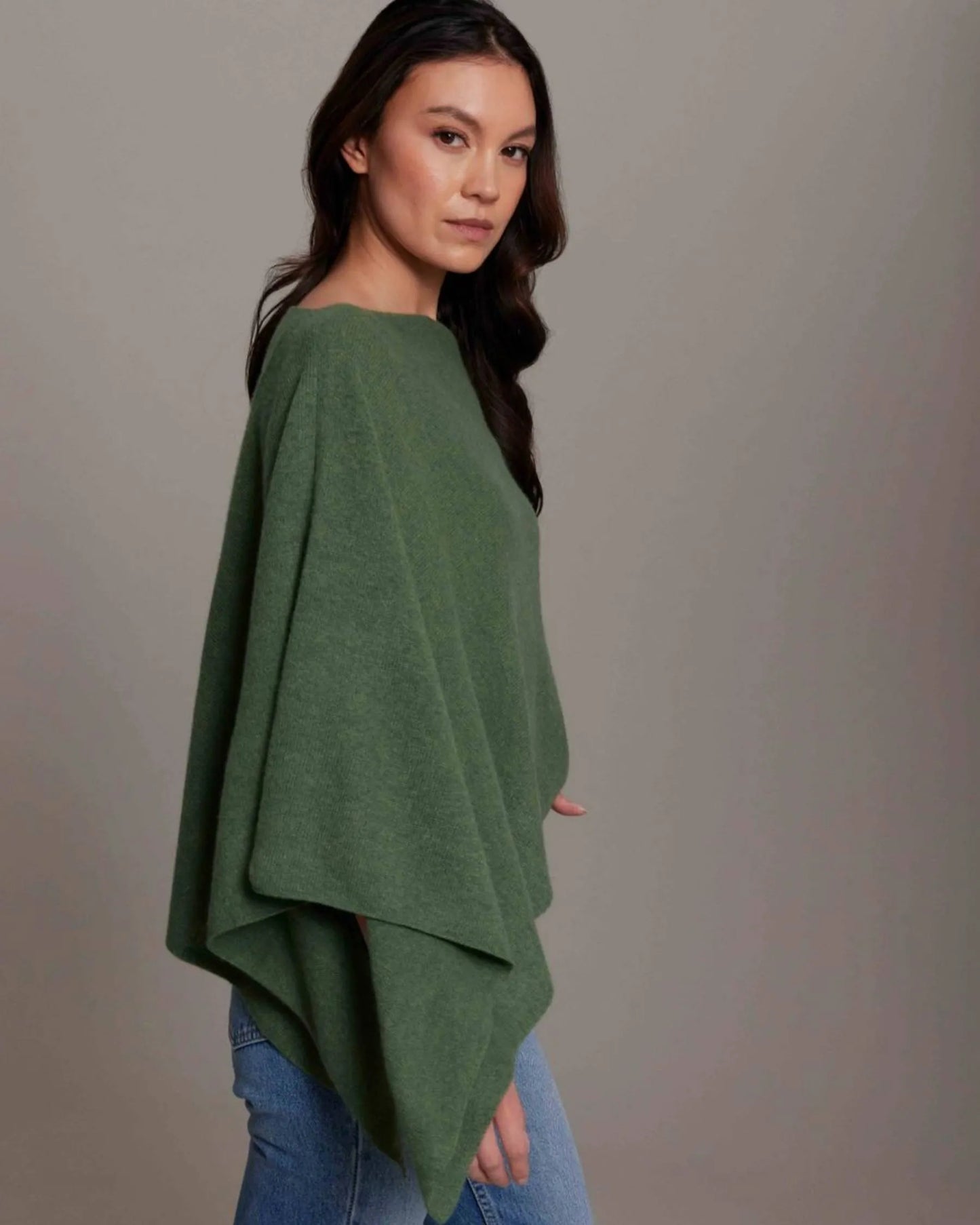 Woman wearing a green poncho against a gray background